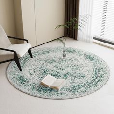 a living room with a rug, chair and book on the floor in front of a window