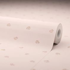 a roll of white paper with small gold dots on it and a light pink background