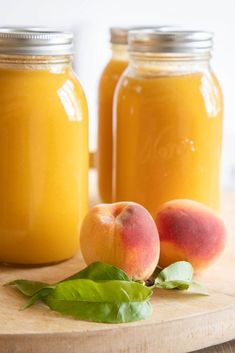 two jars filled with peaches sitting on top of a cutting board next to each other