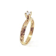 a yellow gold ring with an intricate design and a single diamond in the center, on a white background