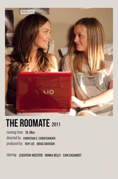 two women sitting next to each other in front of a red laptop on a bed