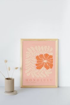 an orange and white flower on a pink background next to a vase with flowers in it