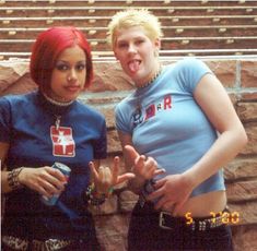 two women standing next to each other in front of a stone wall with their mouths open