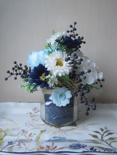 a vase filled with lots of blue and white flowers on top of a table cloth