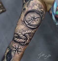 a man's arm with a compass, rope and fish tattoo on the sleeve