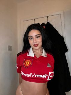 a woman in a red shirt and white panties posing for the camera with her soccer jersey on