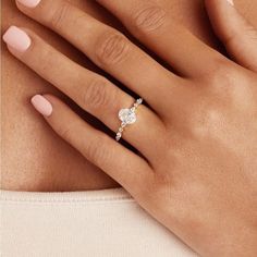 a woman's hand with a diamond ring on her left hand and pink manicured nails