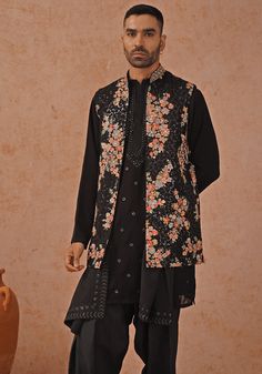 Make a lasting impression with Black Jacket Kurta. Crafted from georgette, the jacket features resham and sequinned embroidery. The yoke design kurta boasts all-over motifs, two pockets, and pure lining. Completed with an embroidered dupatta and patiyala pant. Perfect for Cocktail parties. Composition : Jacket, Kurta, Patiyala pant & Dupatta : Viscose Georgette Care: Dry Clean Only and Vacuum Storage This product can be customized for sleeves, length and colour Delivery : 4-6 weeks as the product is hand crafted. Check Size Guide or choose MySize for free customisation (All Sizes above XL can be made at 15% additional cost) For more information and sizes please contact fabiliciousfashion@gmail.com or visit our Copenhagen studio. About the Designer : Welcome to Kalpraag, your destination fo Festive Floral Embroidered Designer Outerwear, Festival Straight Kurta With Chikankari Embroidery, Chikankari Embroidery Straight Kurta For Festivals, Festive Straight Kurta Outerwear With Floral Embroidery, Festive Chikankari Embroidered Straight Kurta Outerwear, Festive Nehru Jacket With Chikankari Embroidery For Fall, Festive Printed Kurta For Fall, Traditional Sets With Printed Motifs For Winter, Festive Fall Kurta With Printed Motifs