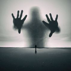 a person standing in front of a giant shadow with their hands out to the side