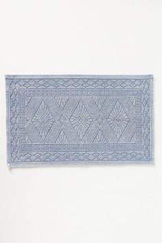 a blue rug on a white wall with an intricate design in the center and bottom