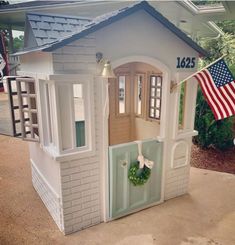 a doll house with an american flag hanging from it's front door and windows