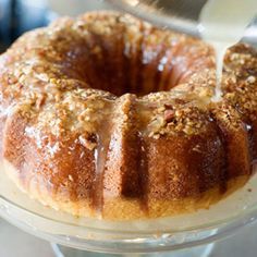 a bundt cake is being drizzled with icing and topped with nuts