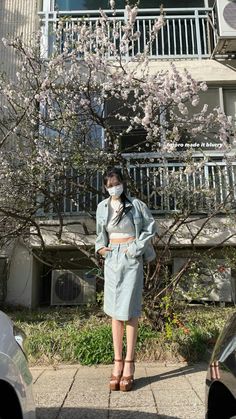 a woman wearing a face mask standing in front of a tree