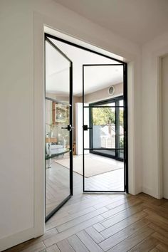 an open door leading into a room with wood flooring and white walls on either side