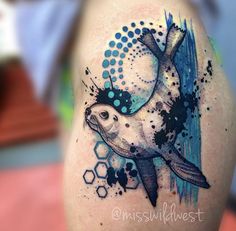 a tattoo with a sea animal on it's arm and watercolor paint splatters