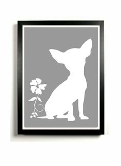 a dog sitting next to a flower in a black frame on a white wall,