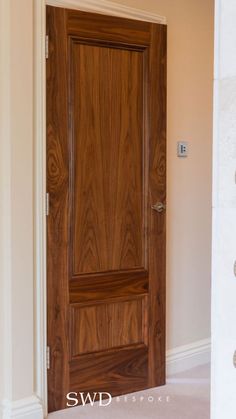 a wooden door in the corner of a room with white walls and carpeted floor