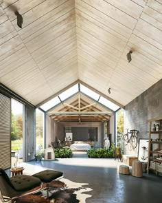 a large open room with a bed in the center and lots of plants on the floor