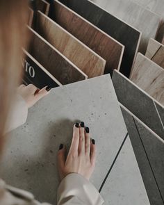 a woman's hand on top of a tile floor in front of several tiles