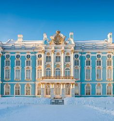 a large blue and white building in the middle of snow covered ground with trees on each side