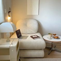 a laptop computer sitting on top of a white chair next to a small coffee table