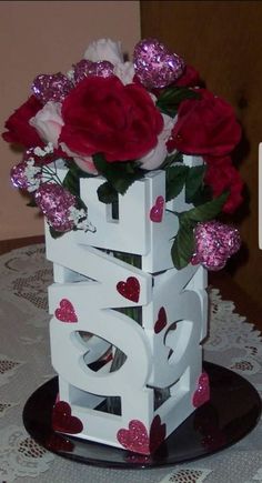 a vase filled with red and white flowers on top of a doily covered table