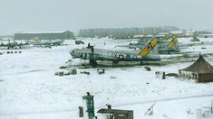 airplanes are parked in the snow at an air field with tents and buildings behind them