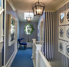 a hallway with striped walls and blue carpeted flooring next to a light hanging from the ceiling