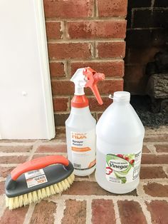 two cleaning products sitting on the ground next to a brick fireplace