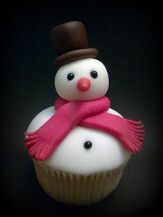 a cupcake with a frosting snowman on top and a pink scarf around it