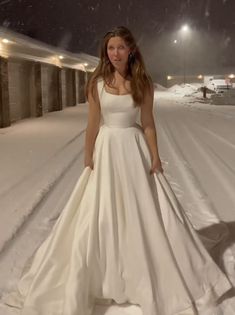 a woman standing in the snow wearing a white dress