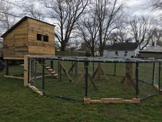 a small wooden house behind a fenced in area with a doghouse on the other side