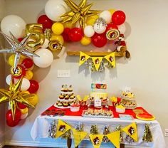 a birthday party with balloons, decorations and desserts on a table in front of a wall