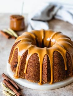 a bundt cake with caramel glaze on top and cinnamon sticks next to it