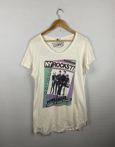 a white t - shirt hanging on a hanger with the words ny rocks 7