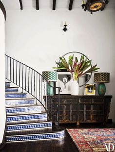 there is a plant on top of a dresser in the living room with stairs leading up to it