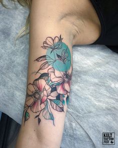 a woman's arm with flowers on it and a blue circle in the middle