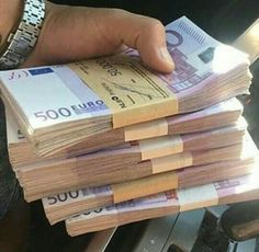 a person is holding stacks of money in their left hand, with the other hand on top of them