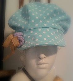 a white mannequin head wearing a blue hat with polka dots and a bow