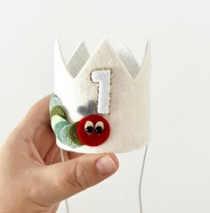 a hand holding a small white crown with a number 1 on it