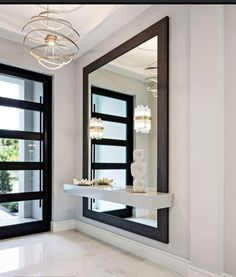 a large mirror sitting on top of a white counter next to a door and window