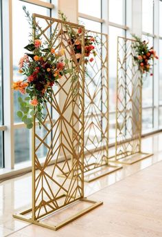 flowers are placed in vases on gold stands