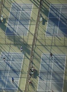 an overhead view of people playing tennis on a court with shadows from the roof and overhangs