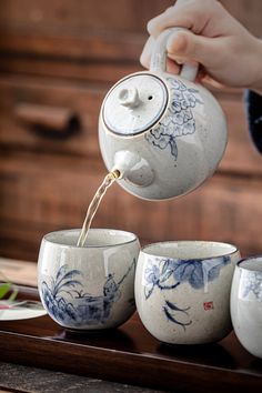 a person pouring water into three cups