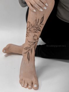 a woman's foot with flowers on it and her hands resting on the ground