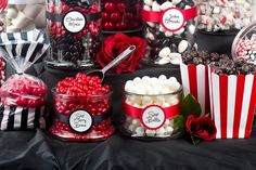 a table filled with lots of candy and candies on top of black cloth covered tables