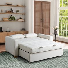 a white couch sitting on top of a rug in a living room next to a window