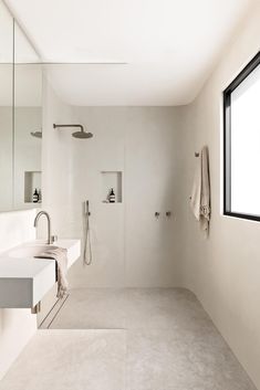 a bathroom with a sink, mirror and shower head mounted to the side of the wall