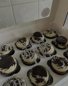 cupcakes with oreo cookies and cream frosting in a box on a counter