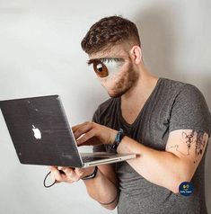 a man with eyeballs on his face using a laptop